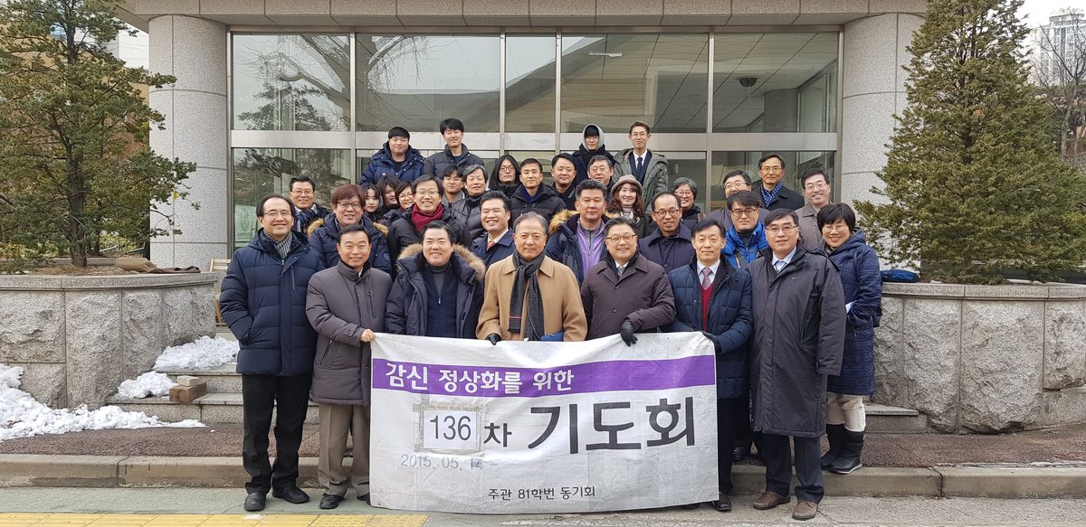 「감신 정상화를 위한 136차 기도회」 현수막을 들고 계단 앞에 모여 선 동문들