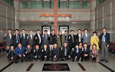 십자가 앞에서 팔을 들어 올린 동문들의 단체사진